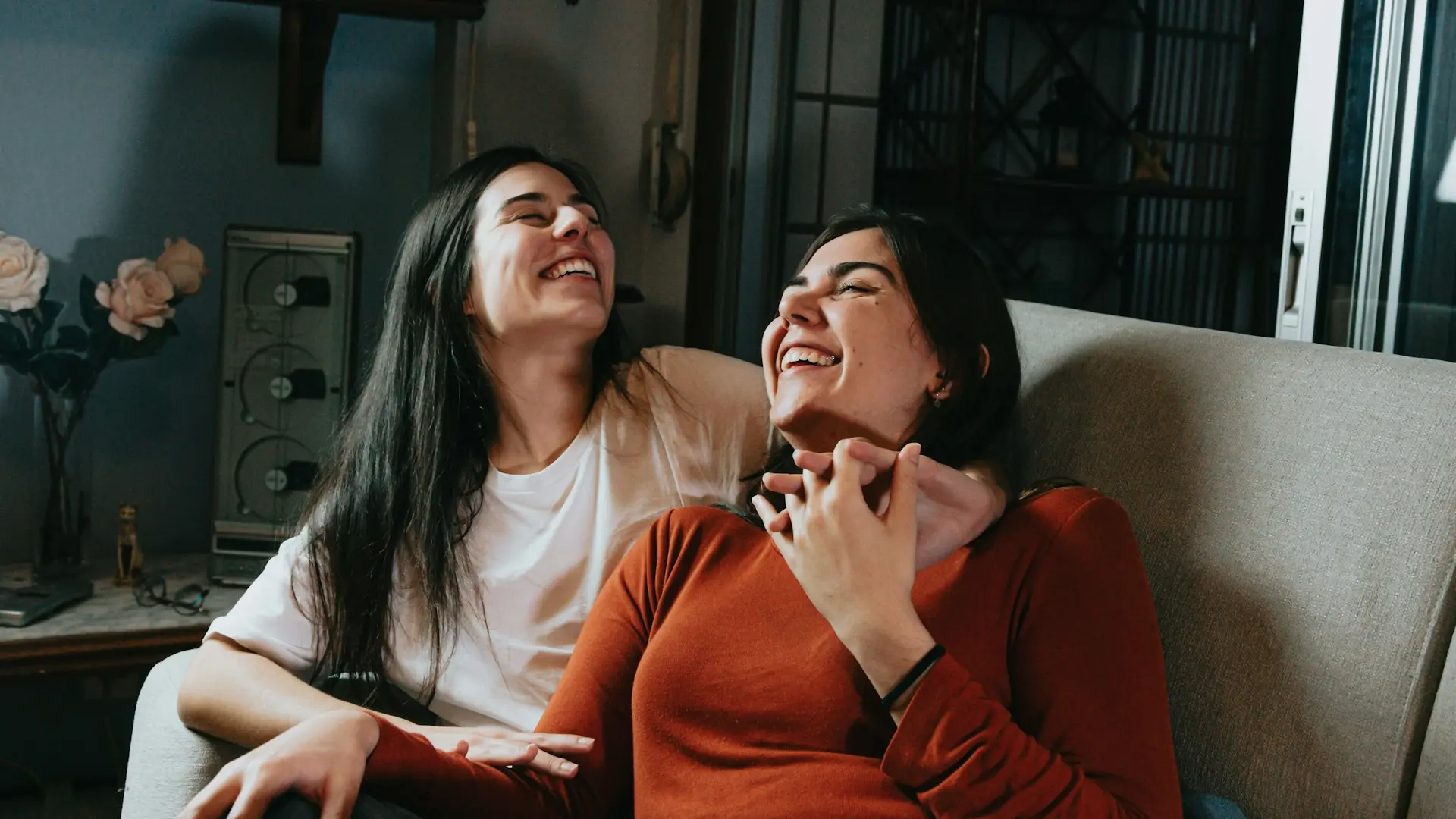 woman in red long sleeve shirt sitting beside woman in white long sleeve shirt